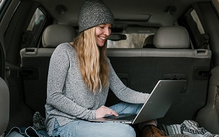 woman on a laptop in the back of her car